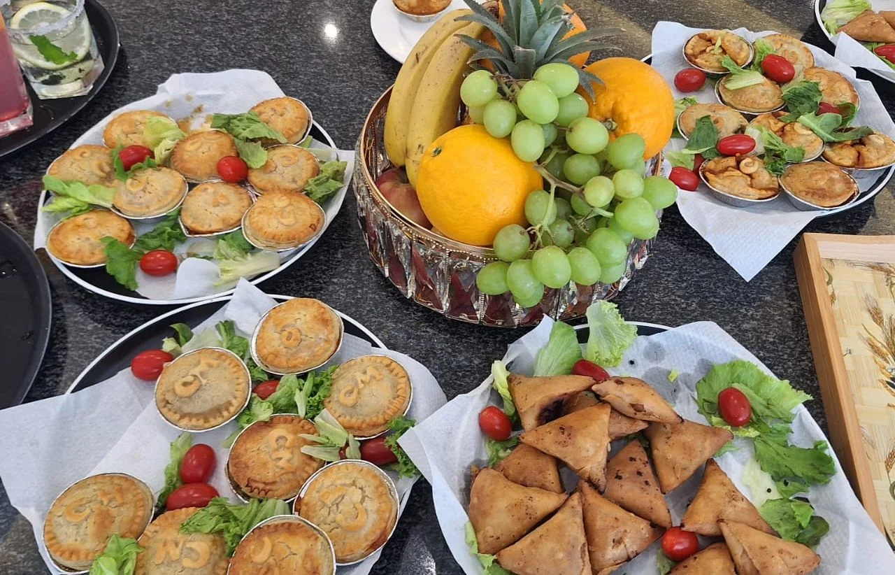 A catering spread of pies, samoosas and fruit