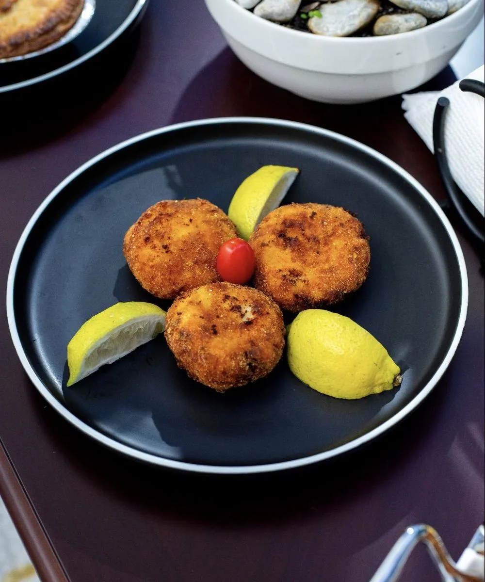 Giant fish cakes on a dark plate with lemon
