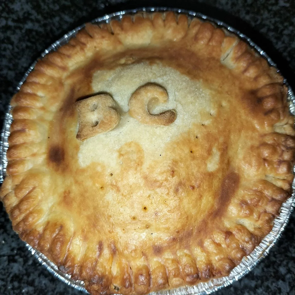 A baked pie with a BC stamp on the crust, the kitchen's code for butter chicken